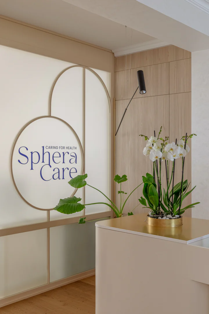 Backlit Sphera Care logo detail with orchids on the reception desk