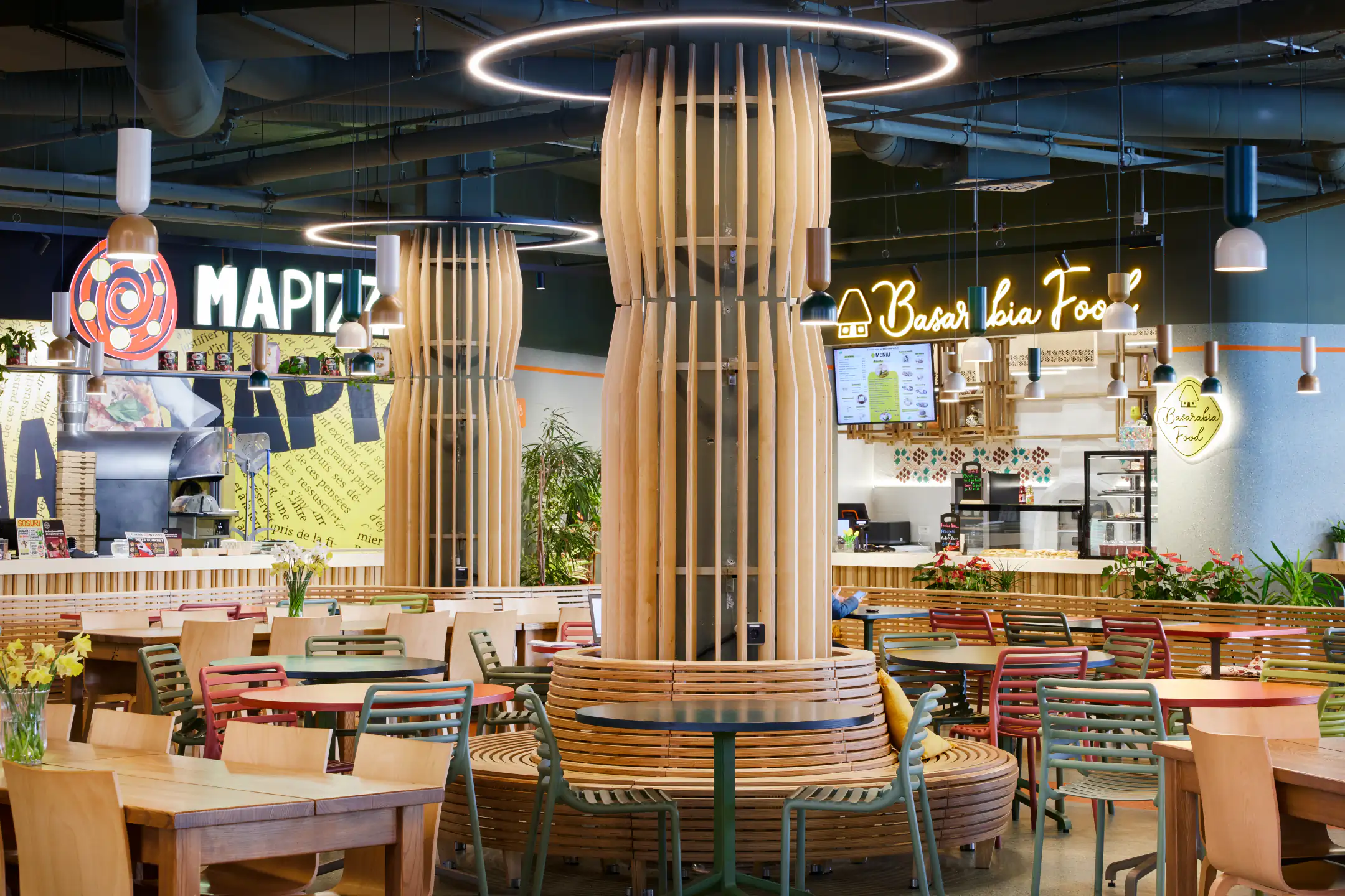 Decorative wooden columns and ring lights in the food court, with Mapizza and BaberLia counters in the background